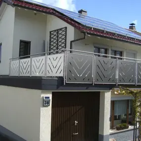Einfamilienhaus mit modernem Edelstahlgeländer am Balkon und Solaranlage auf dem Dach.