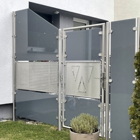 Moderner Sichtschutzzaun aus Glas und Edelstahl mit dekorativem Tor im Vorgarten.
