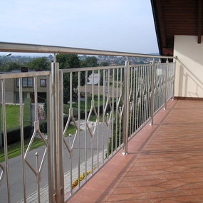 Moderner Balkon mit Edelstahlgeländer und braunen Fliesen, Ausblick auf Wohnsiedlung.